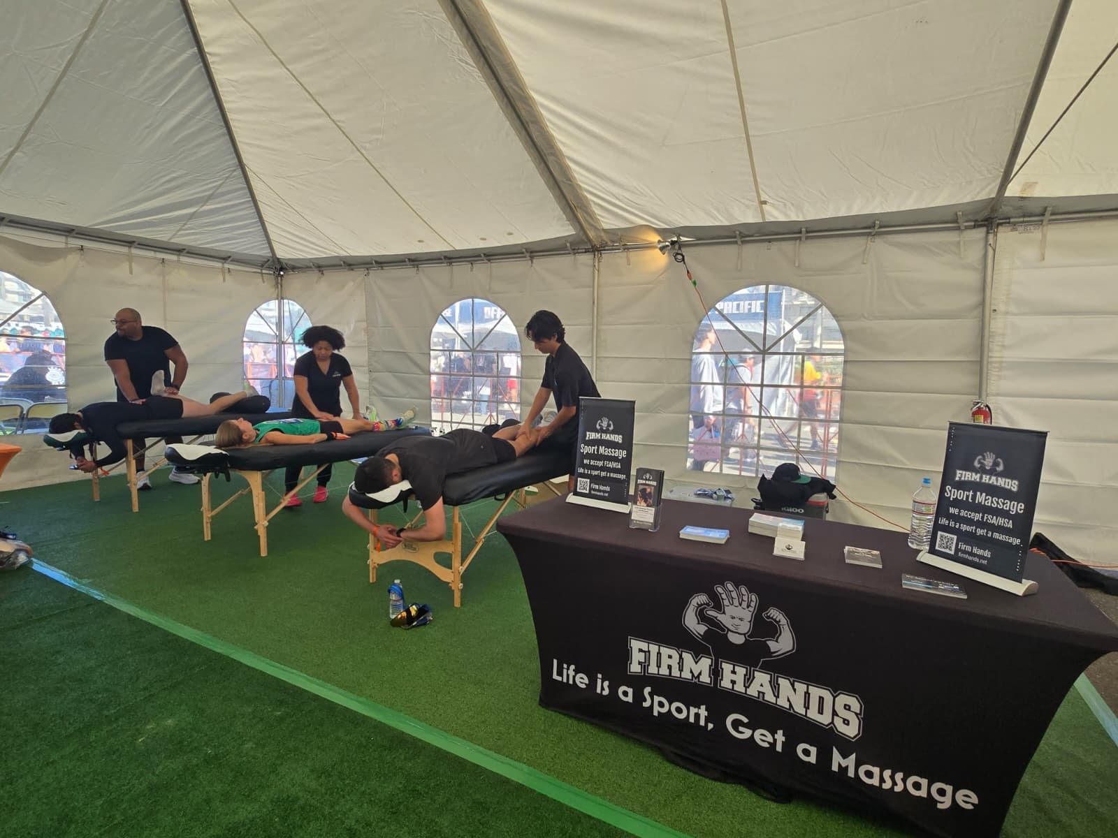 Three tables running at once inside a marquee on a turf field