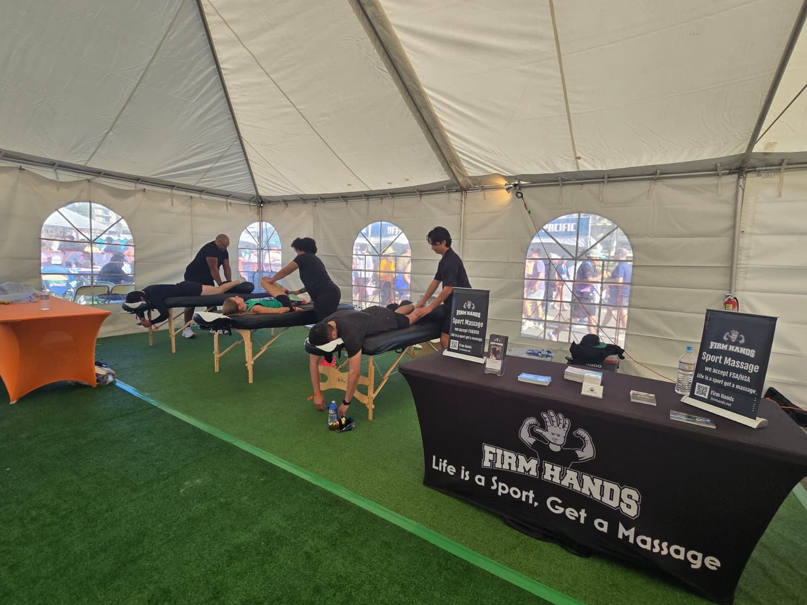 A wider view of the marquee with therapists working on four athletes
