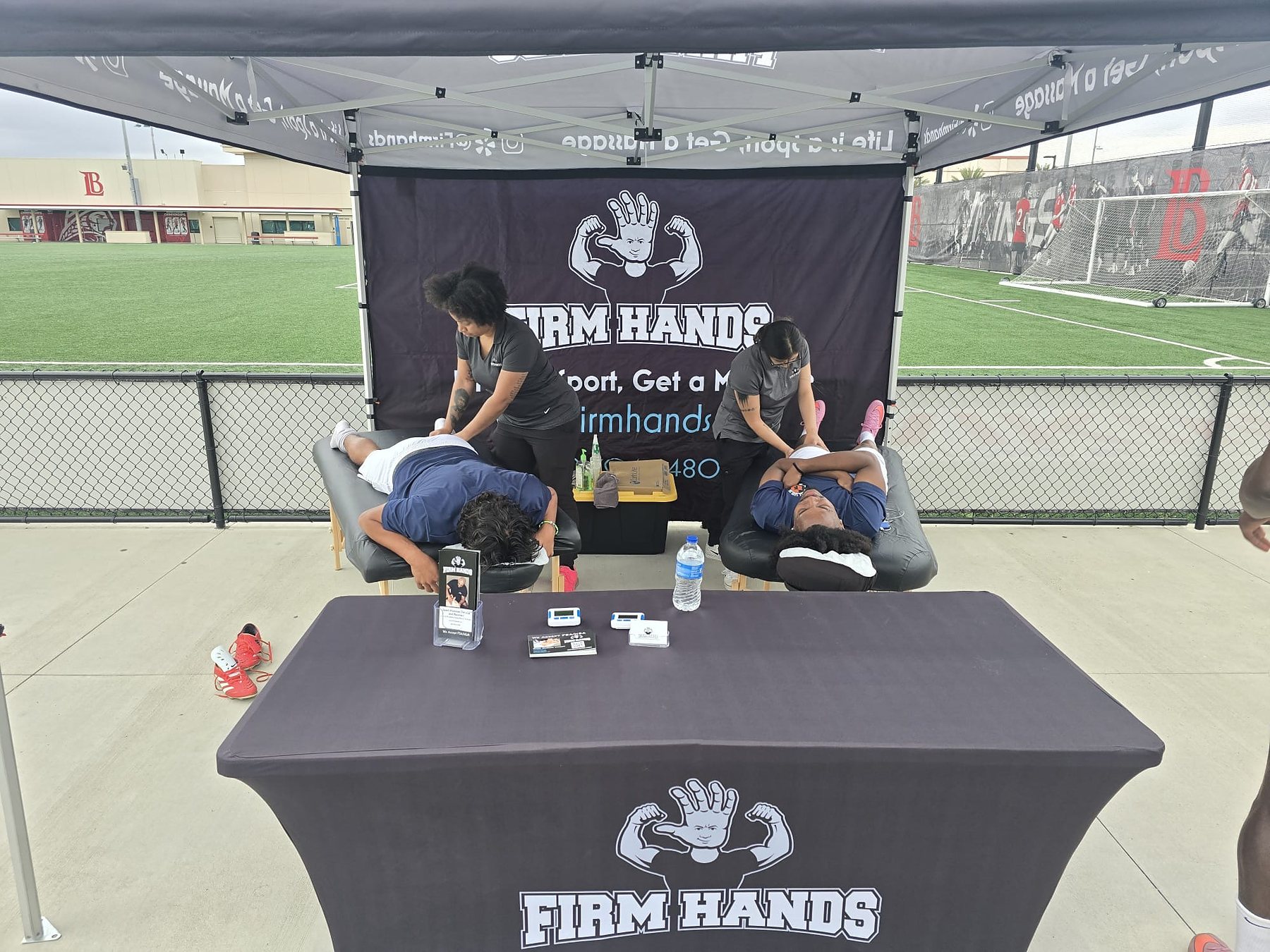 Two young athletes on Firm Hands tables beside their school playing field