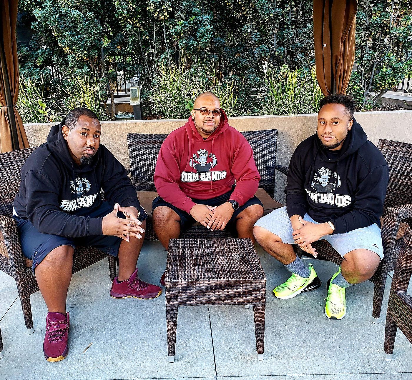 Three Firm Hands therapists in branded hoodies on the studio patio